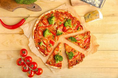 Hafif ahşap arka planda lezzetli vejetaryen pizzalı parşömen.