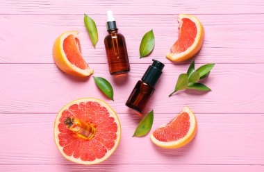 Renkli ahşap arka planda gerekli yağ ve greyfurt dilimlerinin bulunduğu kompozisyon