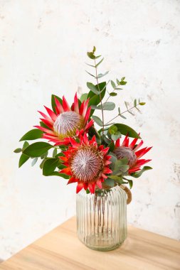 Işık duvarının yanında protea çiçekleri olan masa, yakın plan.