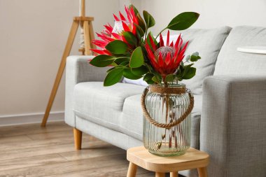 Odanın içinde protea çiçekleri ve kanepe olan bir masa.