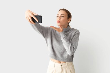 Genç bir kadın arka planda selfie çekiyor.