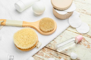 Hafif ahşap arka planda farklı masaj fırçaları ve banyo malzemeleri.