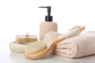 Masaj fırçası ve beyaz arka planda farklı banyo malzemeleri.