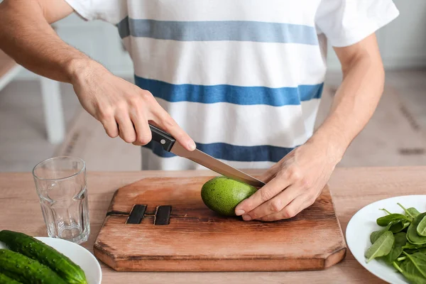Young Man Cutting Fresh Avocado Kitchen — Stock fotografie