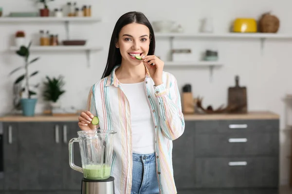 Young Woman Eating Cucumber While Preparing Smoothie Kitchen — Foto de Stock