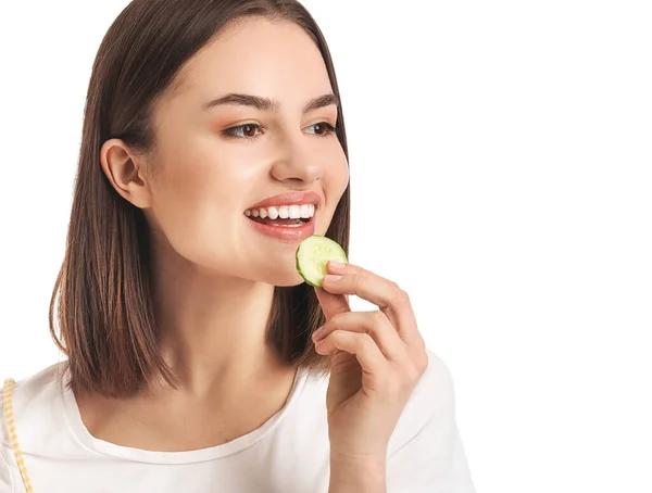 年轻女子吃黄瓜的白色背景 — 图库照片