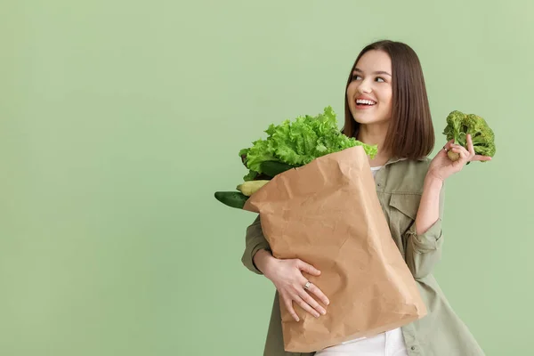 若い女性と色の背景に新鮮な野菜と紙の袋 — ストック写真