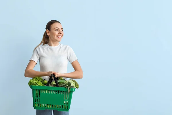 若い女性と色の背景に新鮮な野菜とショッピングバスケット — ストック写真