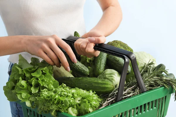 若い女性と色の背景に新鮮な野菜とショッピングバスケット — ストック写真