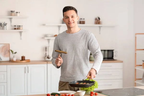 Young Man Frying Tasty Sausages Kitchen — Stock Photo, Image