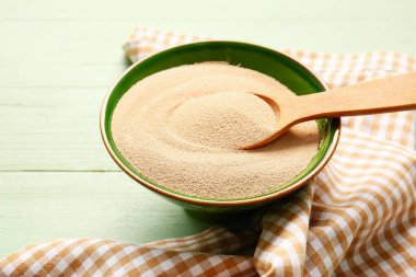 Renkli ahşap arka planda etkin kuru maya ile kase