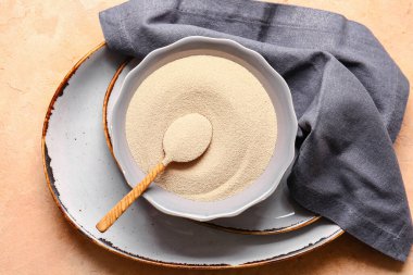 Renk arkaplanında etkin kuru maya olan kase ve kaşık