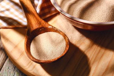 Ahşap arka planda kaşık aktif kuru maya