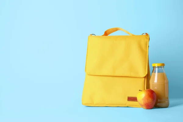 Lunch box bag, bottle of juice and apple on color background