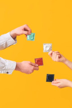 Renkli arka planda prezervatifli çiftlerin elleri