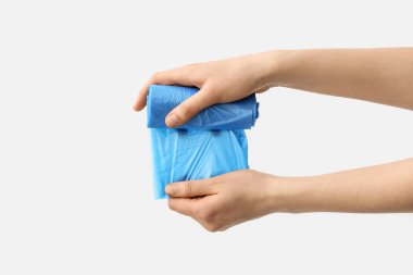 Beyaz arka planda kadın elleri çöp torbasını çözüyor