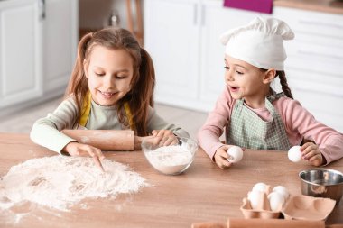 Cute little sisters cooking in kitchen