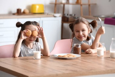 Mutfakta kurabiye yiyen şirin küçük kız kardeşler.