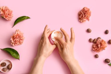 Bir kavanoz tereyağı, fındık ve çiçekli kadın eli.