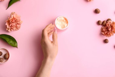 Bir kavanoz tereyağı, fındık ve çiçeklerle dolu kadın eli.