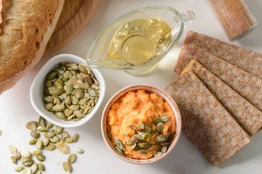 Lezzetli havuç humusu, kabak çekirdeği ve kraker ve hafif arka planda.