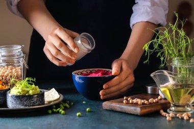 Karanlık masada nefis pancar humusu hazırlayan kadın, yakın plan.