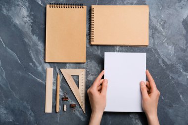 Renk arkaplanı üzerinde boş kağıt ve kırtasiye malzemesi olan kadın elleri