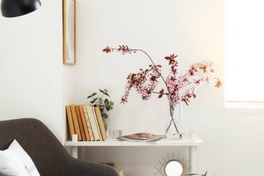 Işık duvarının yanındaki rafta çiçek açan dallar.