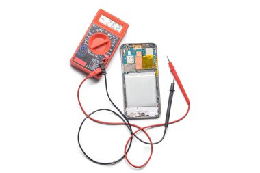 Disassembled mobile phone with multimeter on white background