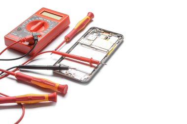 Disassembled mobile phone with multimeter on white background
