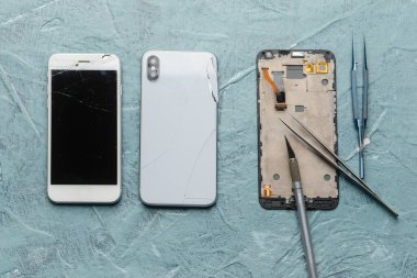 Arkaplanda teknisyen araçları olan hasarlı cep telefonları