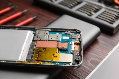 Disassembled mobile phone on wooden background, closeup