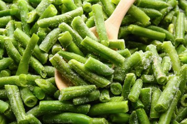 Frozen green beans and spoon as background