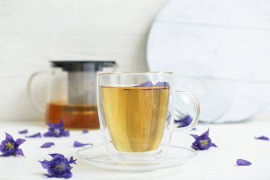 Cup with tasty floral tea on light background