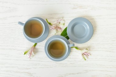 Çiçekli çay bardakları ve hafif ahşap arka planda çiçekler.