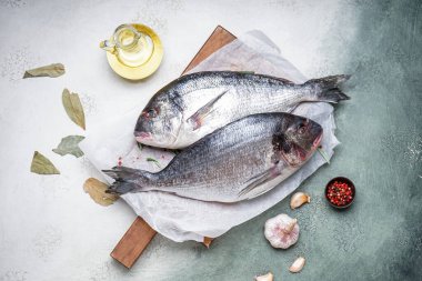 Board with raw dorado fishes on light background