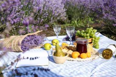 Lavanta tarlasında romantik piknik için lezzetli yemekler ve içecekler.