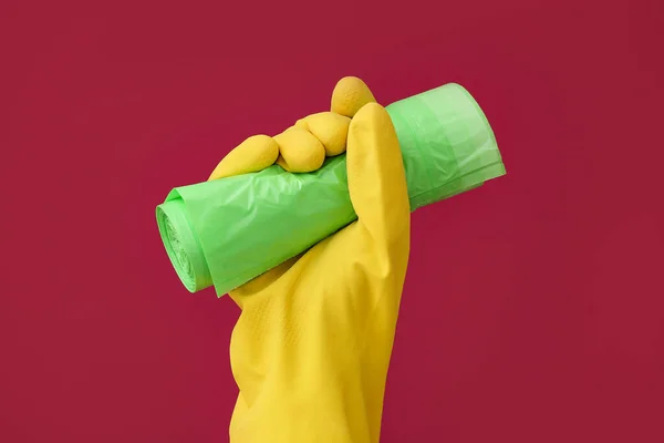 色の背景にゴミ袋のロールとゴム手袋で手 — ストック写真