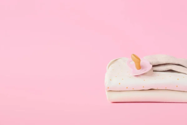 Stapel Babykleidung Und Schnuller Auf Farbigem Hintergrund — Stockfoto