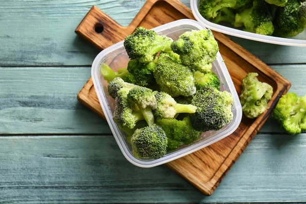 Wadah Dengan Brokoli Beku Pada Warna Latar Belakang Kayu — Stok Foto