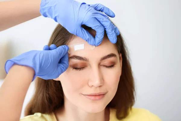 Nurse Applying Medical Patch Young Woman Forehead Clinic — Stock Photo, Image