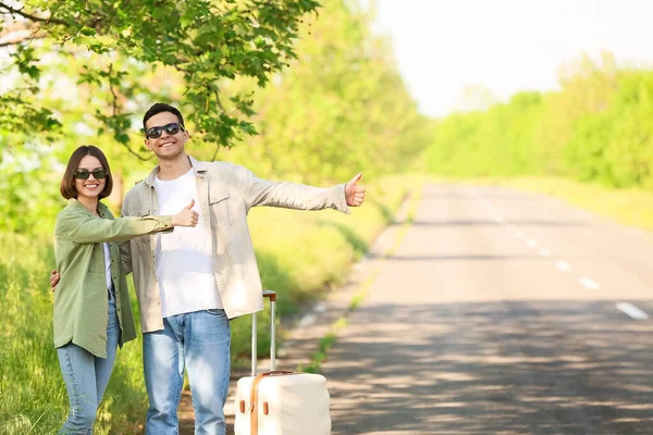 Bavullu Genç Çift Yolda Otostop Çekiyor — Stok fotoğraf