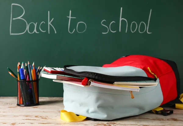 Schulrucksack Mit Schreibwaren Auf Tisch Neben Tafel — Stockfoto