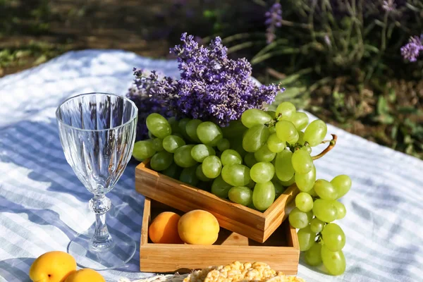 Tasty fruits and wine glass for romantic picnic in lavender field