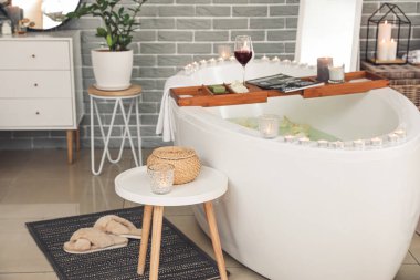 Modern banyonun içinde yanan mumlar ve bir bardak şarap var.