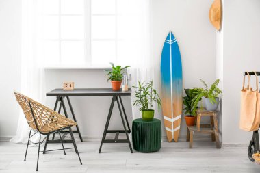 Masası ve sörf tahtası olan modern şık bir oda.