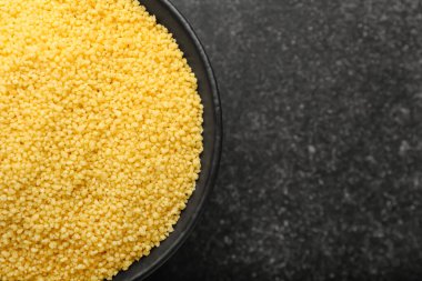 Koyu arka planda ham kuskus olan kase, yakın plan.