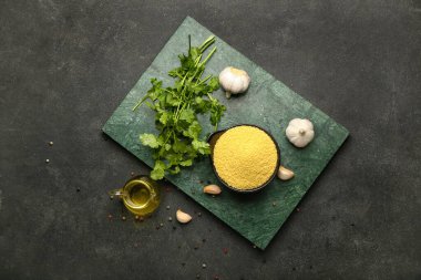 Koyu arkaplanda ham kuskus, baharat ve yağ içeren kompozisyon