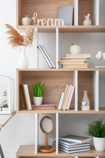 Stylish shelf unit with books and decor in room, closeup