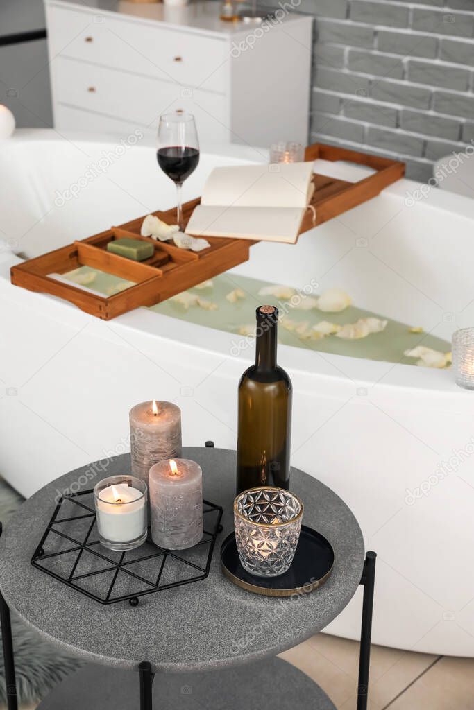 Stylish interior of modern bathroom with burning candles and wine